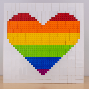 Ein Herz aus Klembausteinen dessen Farben die Pride Flagge bilden.